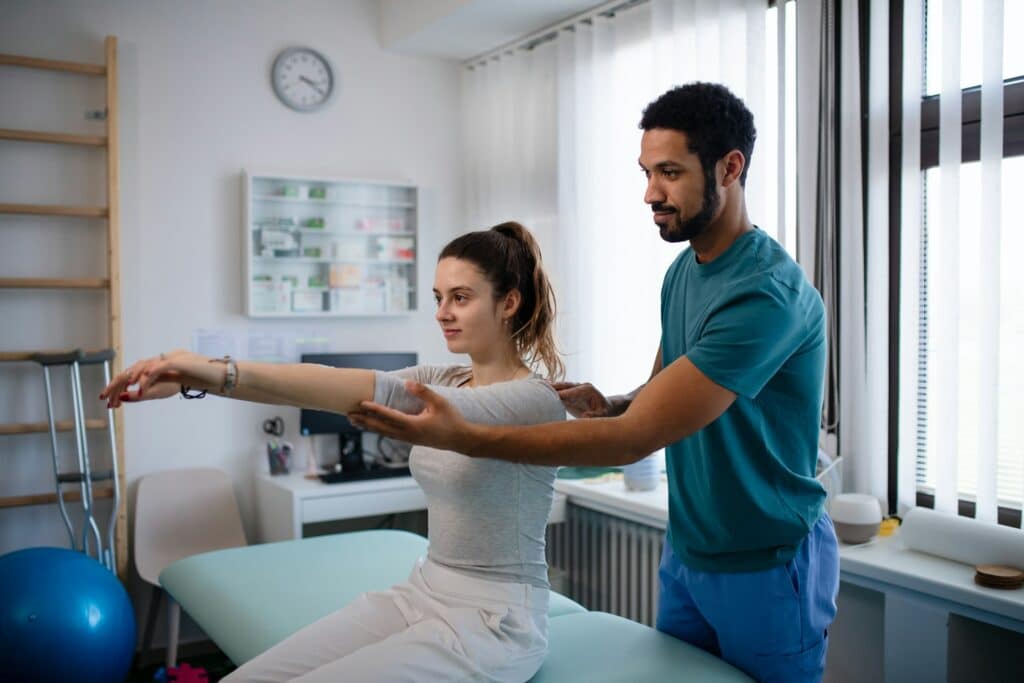 a-young-male-physiotherapist-examining-young-woman-patient